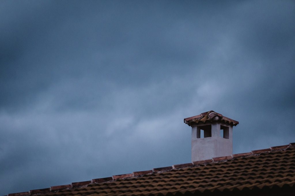 Image of a roof with chimney and cloudy sky