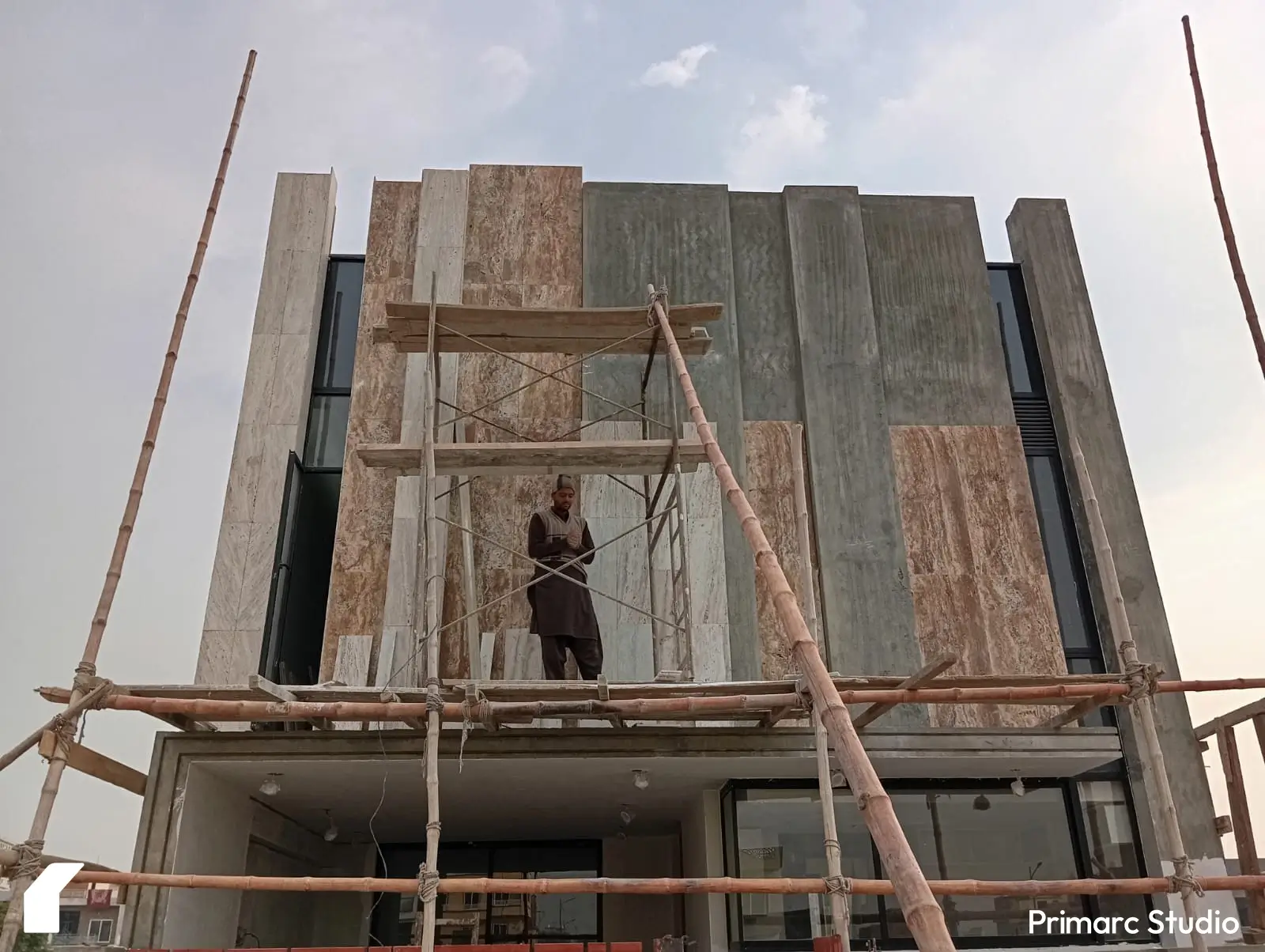 A labor applying stone on the facade of 5 marla house in faisal margalla city, Islamabad