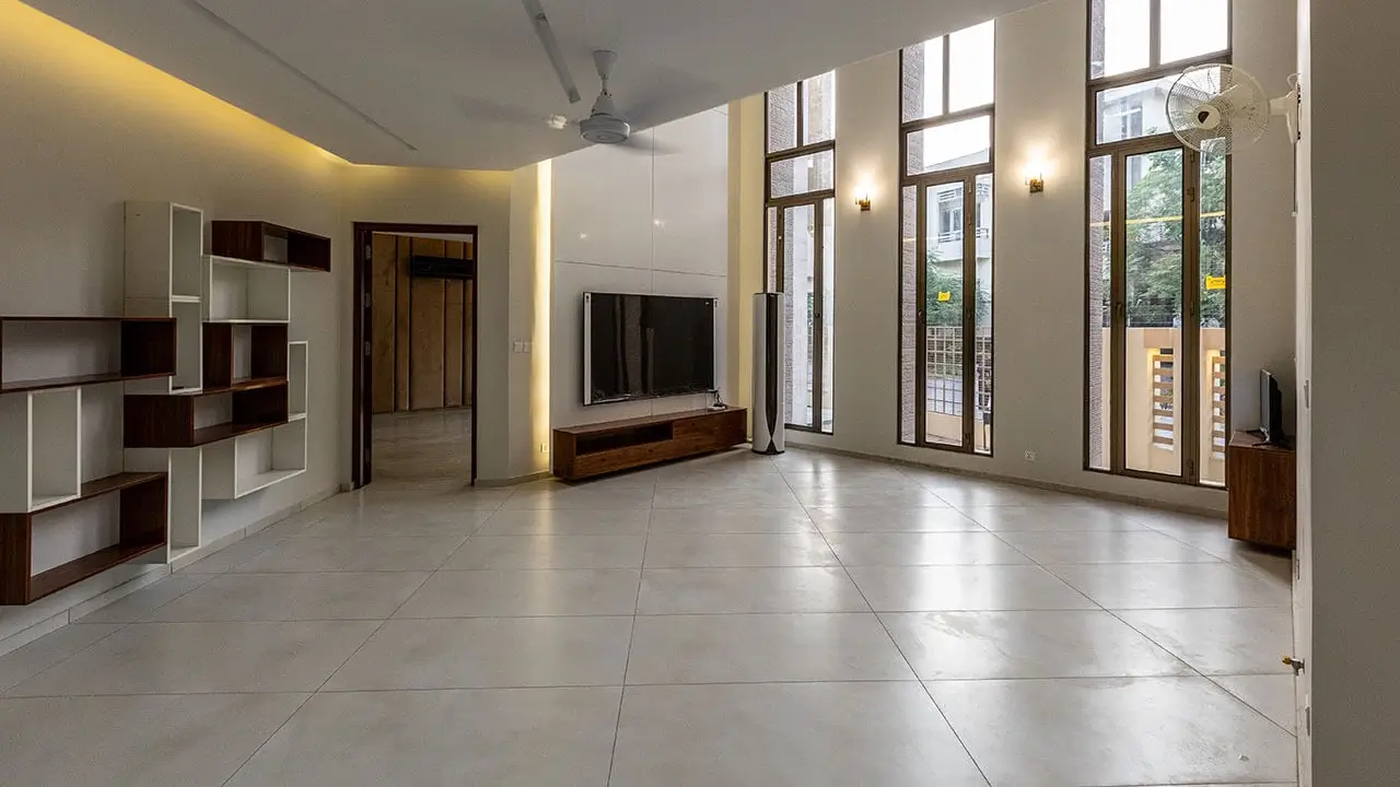 Modern lounge with offwhite ceramic tile flooring, double height space, and long, tall windows.