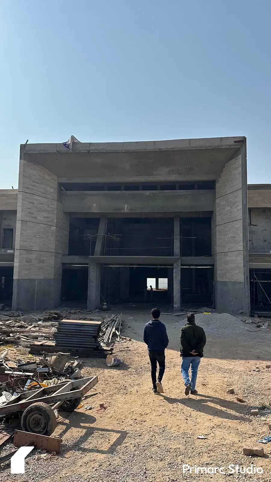 Architect and draftsman walking toward the triple-height entryway of a modern marquee in Islamabad, highlighting the massive scale of the entryway through a human comparison, showcasing contemporary architectural grandeur.