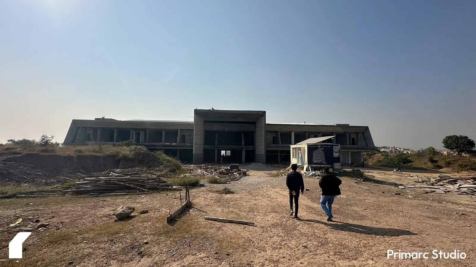 Architect and draftsman walking toward a modern marquee in Islamabad on a sunny winter day. The marquee features a striking triple-height entryway, showcasing contemporary architectural design suited for events and gatherings.