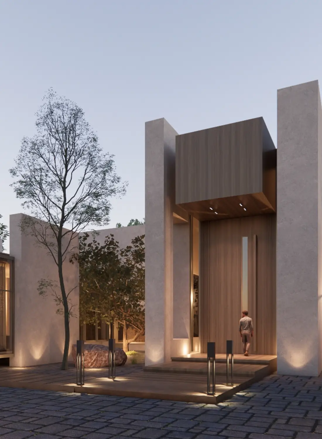 The grand entrance of a modern single-story house designed by Primarc Studio in Khanpur. A large wooden door is recessed within a light-colored structure, flanked by illuminated pathways and landscaping featuring trees and textured walls.
