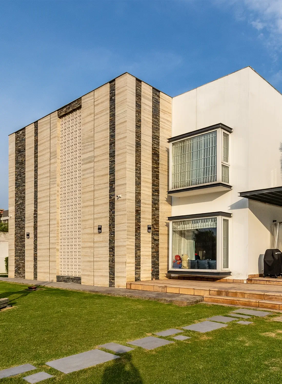 Exterior view of a modern farm house in Gulberg Greens, Islamabad, showcasing the renovated facade designed by Primarc Studio. The image highlights the contemporary architecture, material application, and the newly designed landscape with pathways. This is an example of Primarc Studio's architecture and landscape design services for farm houses in Islamabad.