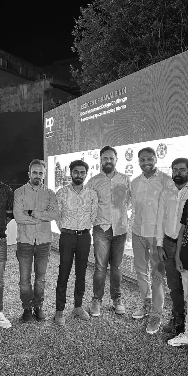 A team of architects stands proudly in front of a backdrop that reads "ECHOES OF RAWALPINDI Urban Monument Design Challenge - Transforming Space-Sculpting Stories." Logos for IAP (Institute of Architects Pakistan) and RDA (Rawalpindi Development Authority) are visible.