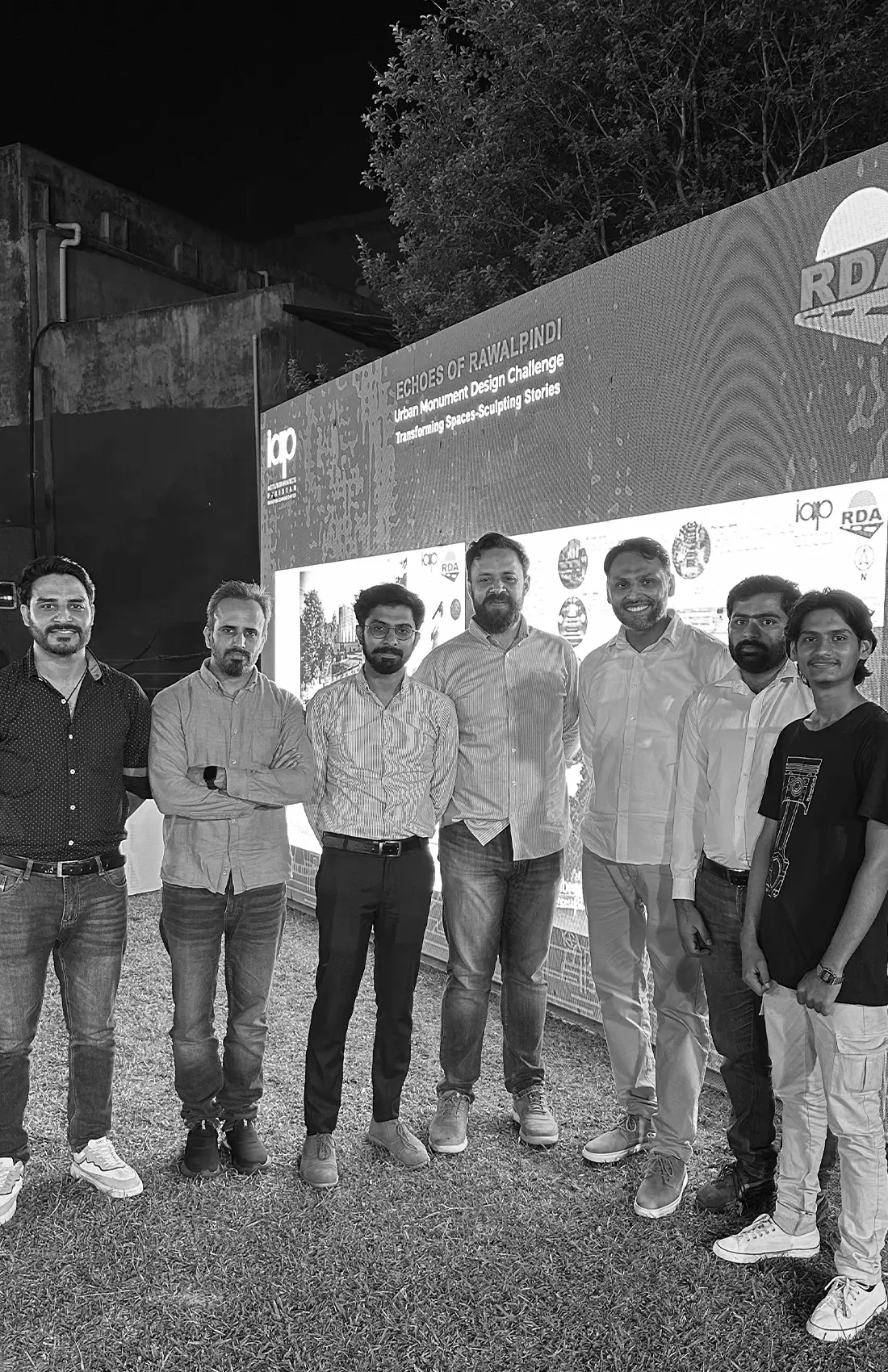 A team of architects stands proudly in front of a backdrop that reads "ECHOES OF RAWALPINDI Urban Monument Design Challenge - Transforming Space-Sculpting Stories." Logos for IAP (Institute of Architects Pakistan) and RDA (Rawalpindi Development Authority) are visible.