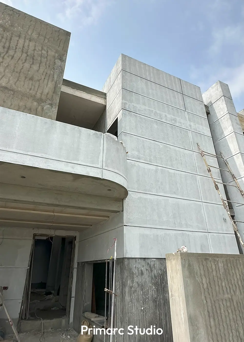 Exterior of a multi-story minimalist house under construction, featuring concrete facades and clean lines against a sky.