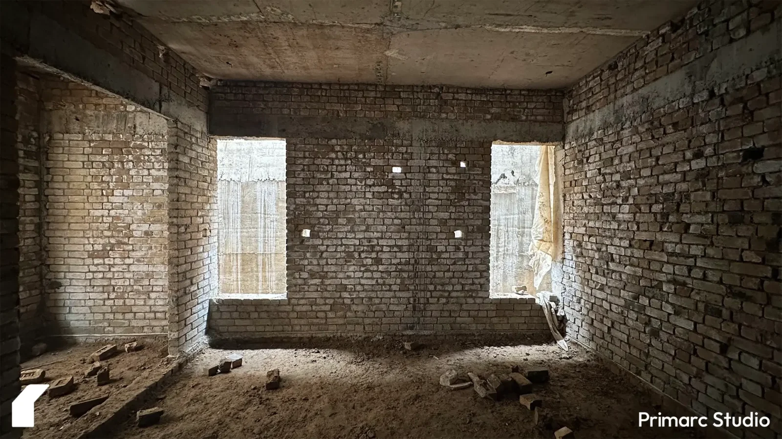 The interior of a room under construction, with exposed brick walls and openings for large windows. This highlights the "grey structure" phase of the project.