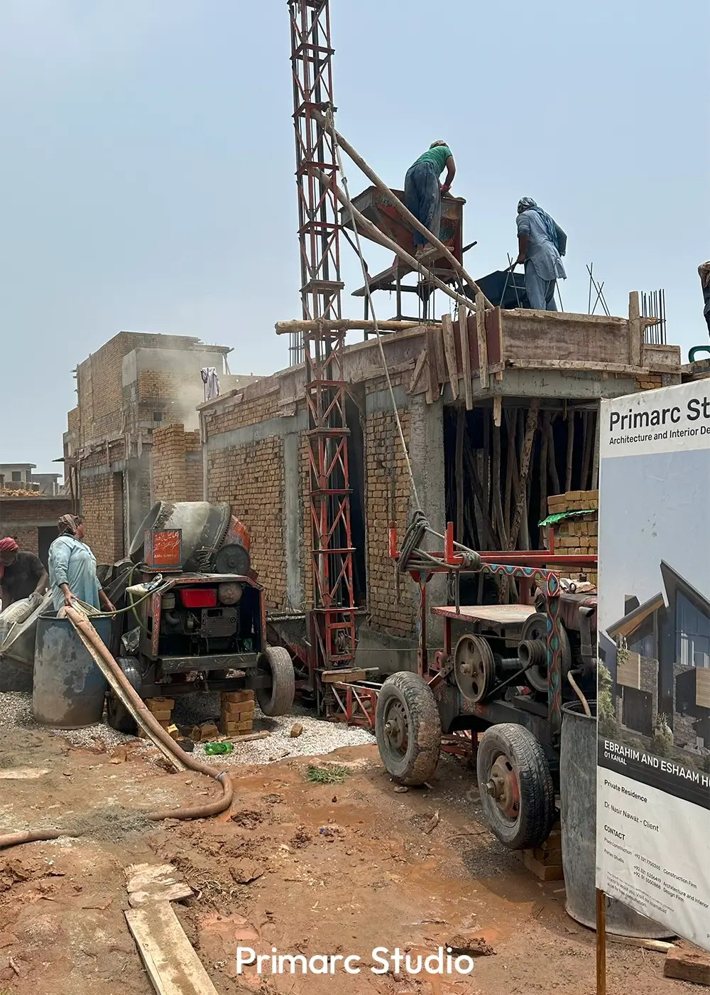 Construction workers pouring concrete for a house roof slab using traditional scaffolding and equipment on a sunny day.