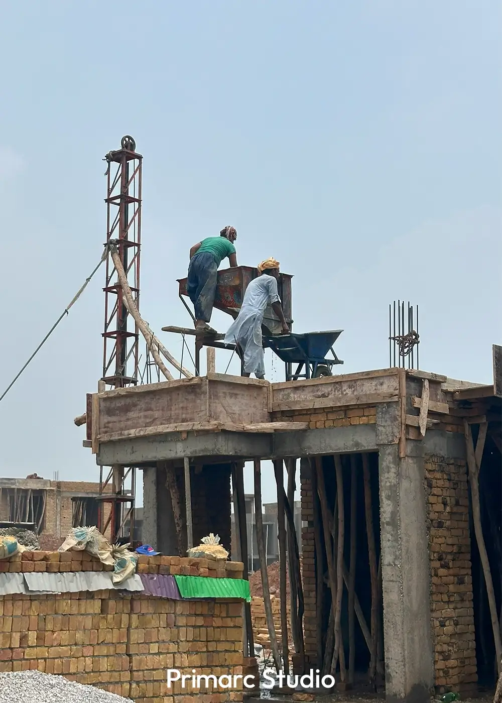 Close-up of construction workers on a partially built roof, preparing for concrete work with a cement hoist.