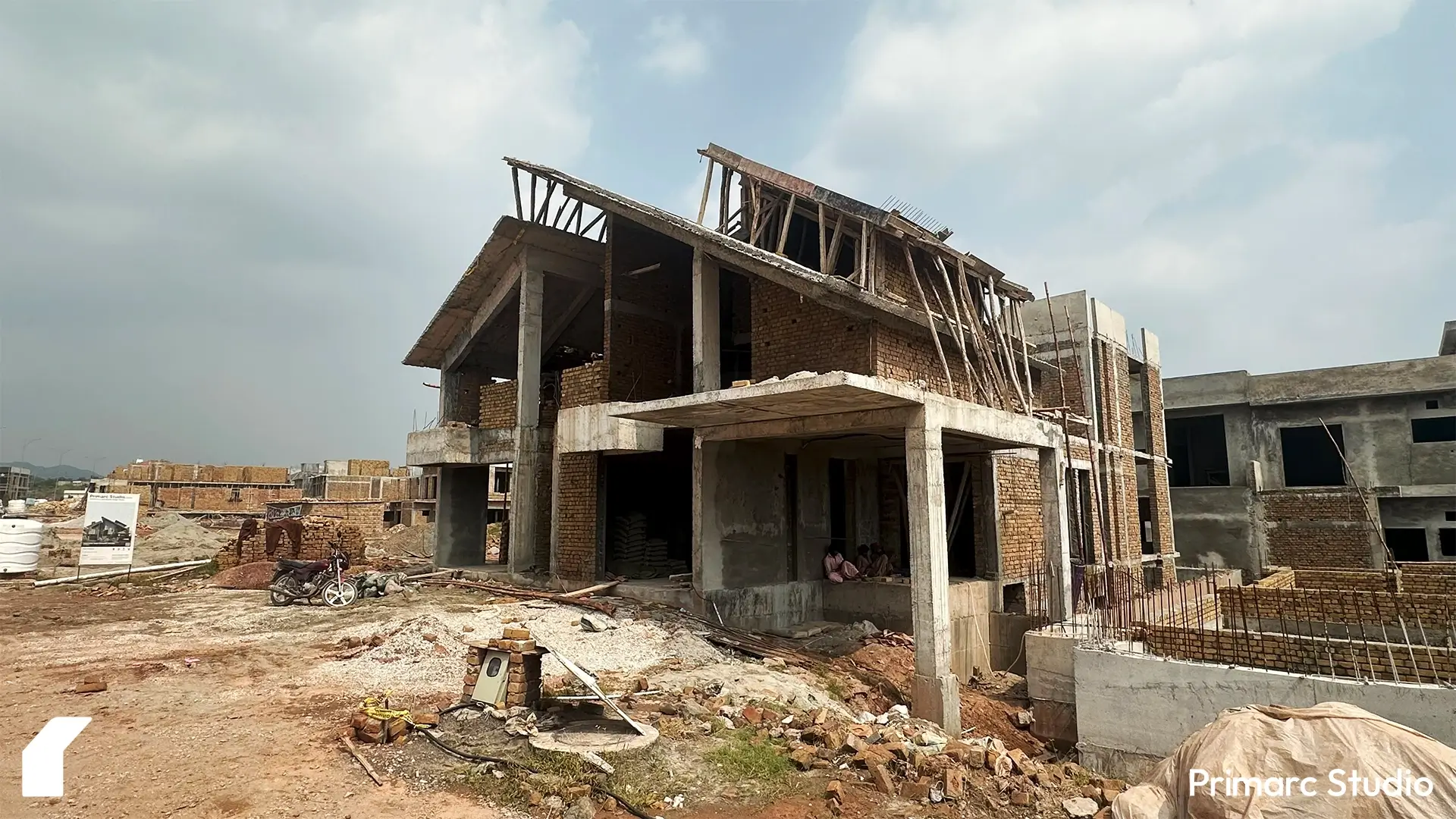 Front view of contemporary one kanal house in Park View City Islamabad, showing exposed brickwork, concrete structure, and sloping roof framework during construction.