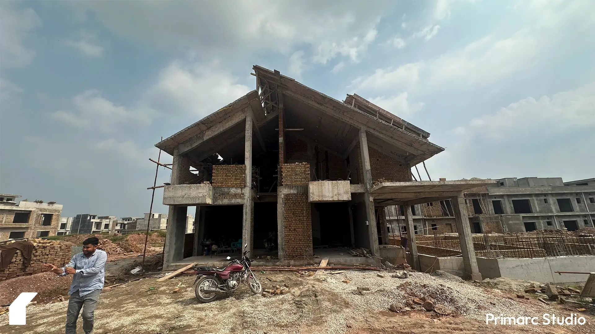 Construction progress of contemporary house in Park View City Islamabad with symmetrical columns, angular roofline, and scaffolding on brick walls.