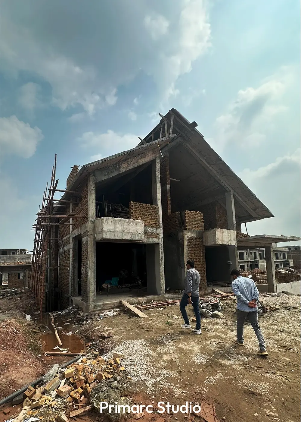 Workers inspecting the construction of a contemporary one kanal house in Park View City, highlighting steep angular rooflines and brick façade.