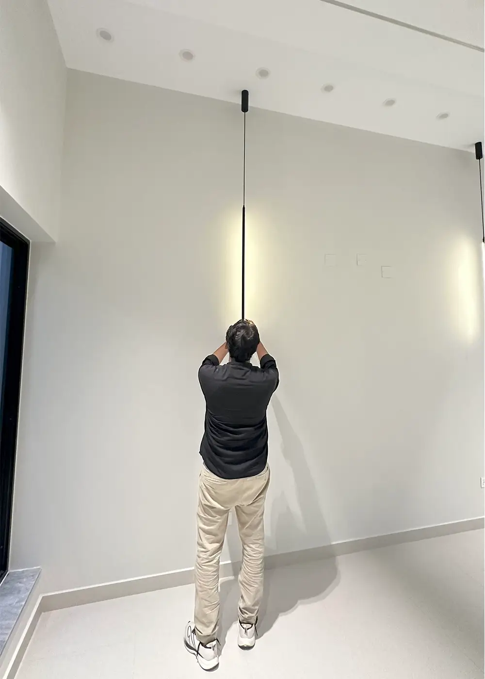 Worker adjusting modern pendant light inside 10 marla modern house Gulberg Residencia Islamabad.