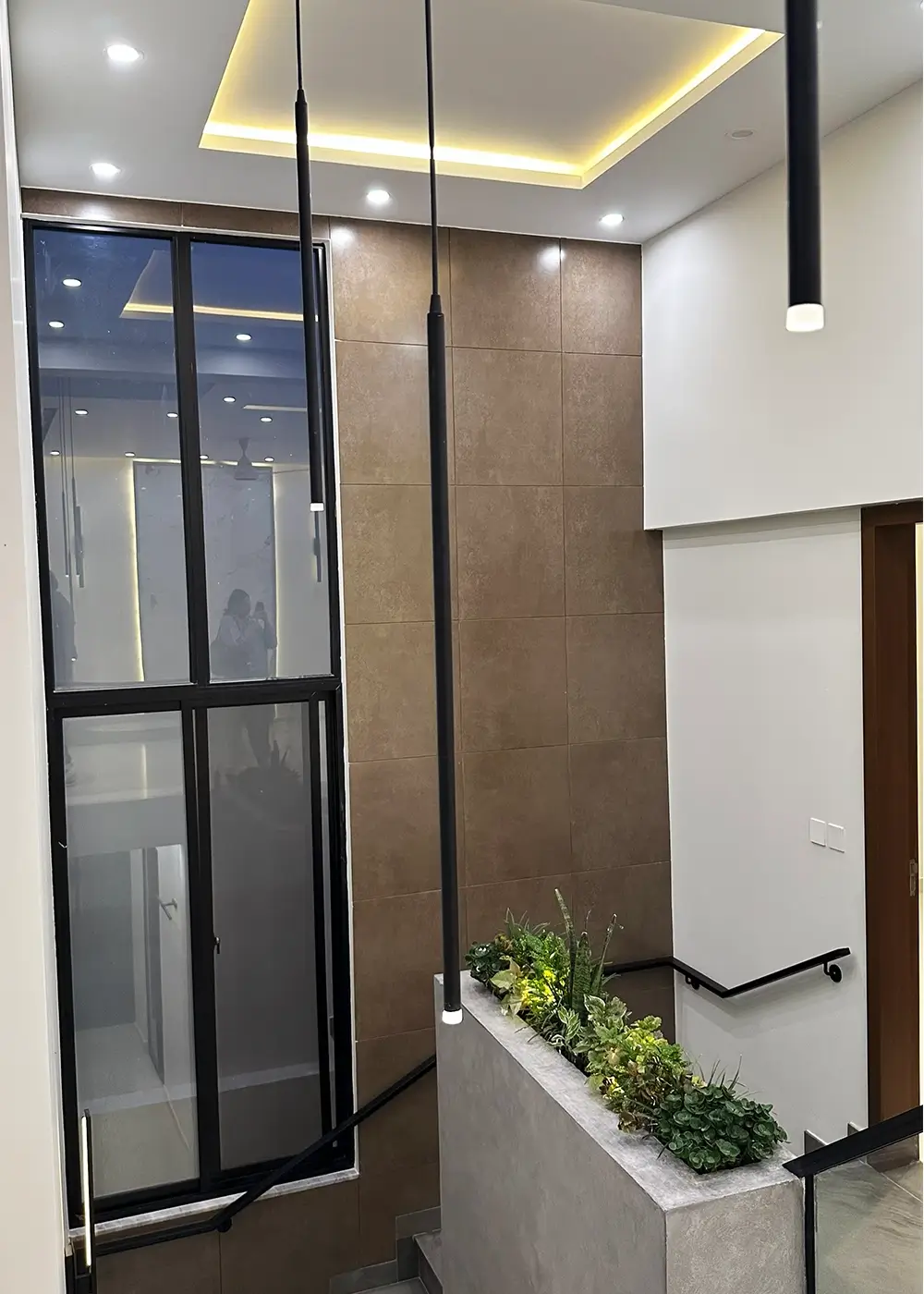 Modern atrium with pendant lights and indoor plants in 10 marla house Gulberg Residencia Islamabad.