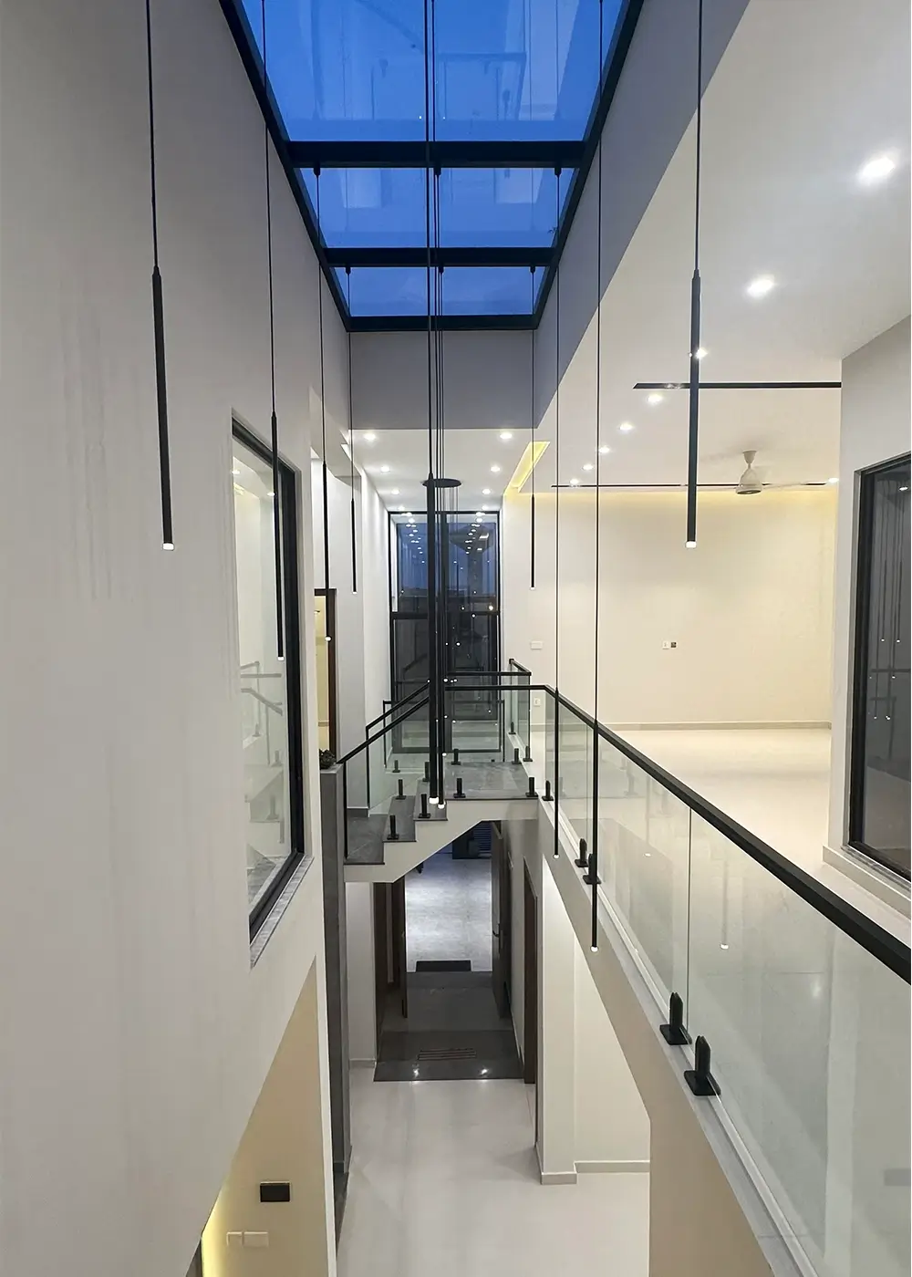 First floor glass railing walkway with skylight and pendant lights in 10 marla house Gulberg Residencia.