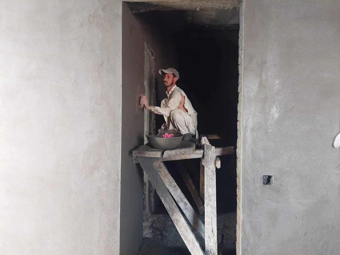 Worker applying plaster to doorway wall inside 1 Kanal residential house in Park View City Islamabad.